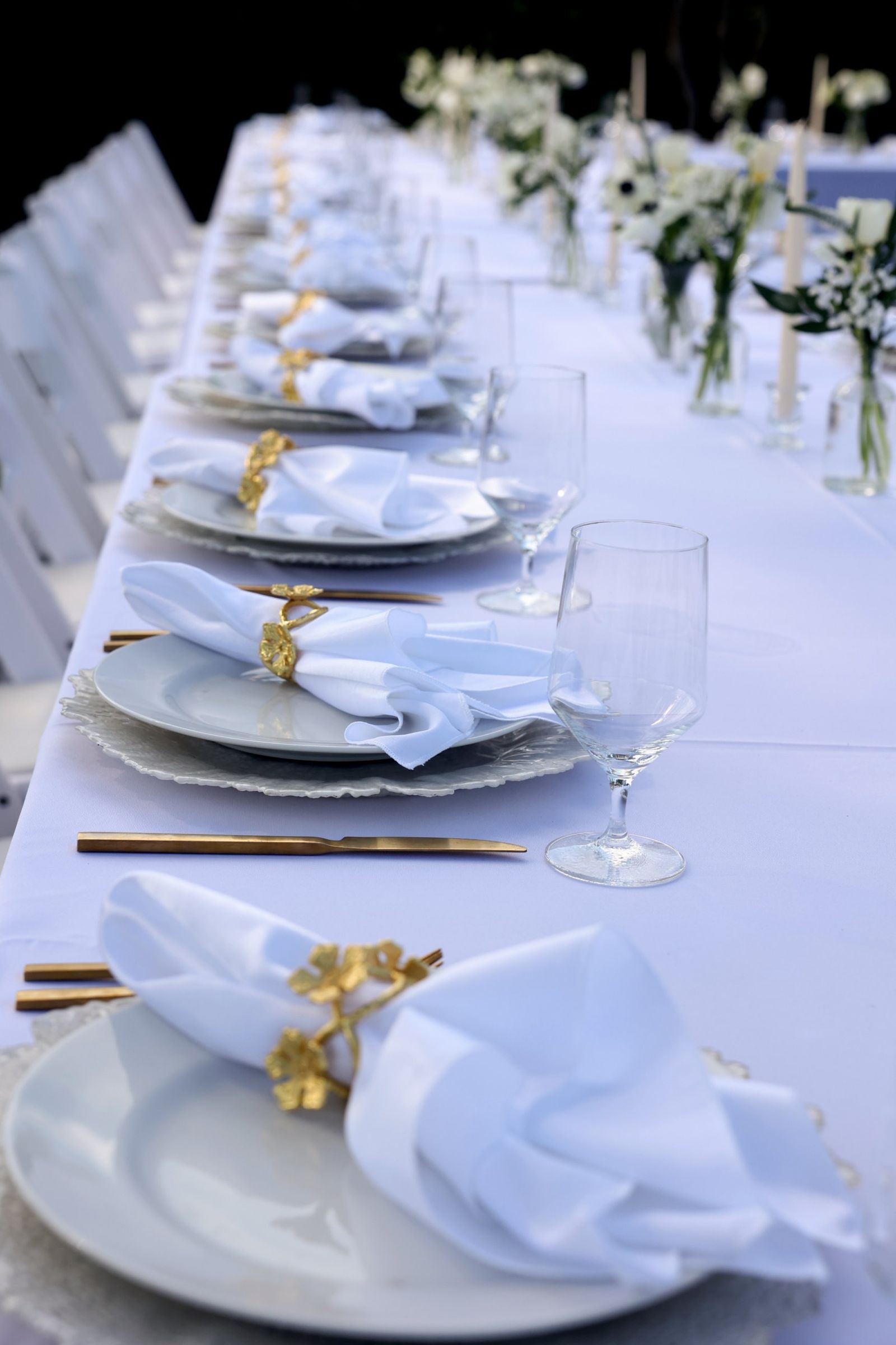 Long white-linen dinner table set with gold accents